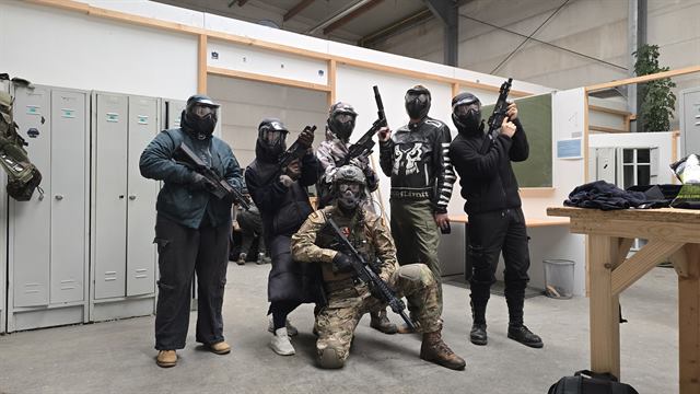 Gruppe von Spielern mit Masken und Repliken in einer Halle, OMUNE kniet vorne